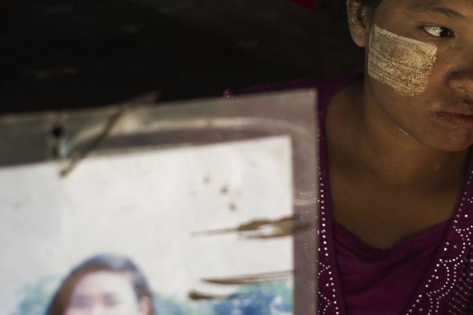 This photo taken on June 30, 2016 shows Mar Tuu holding a photograph of her sister Kyi Pyar Soe on the outskirts of Yangon. Enticed by work in China, hundreds of poor young Myanmar women are instead being duped into marriage, and left to scramble to get back across remote borders before they are forced into life with husbands they have never met. Photo: Ye Aung Thu/AFP

