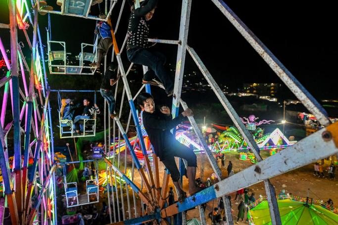 This photo taken on November 6, 2019 shows Aung Sein Phyo (C), 22, and other crew members operating a human-powered ferris wheel in Taunggyi, Shan state. Photo: Ye Aung Thu/AFP