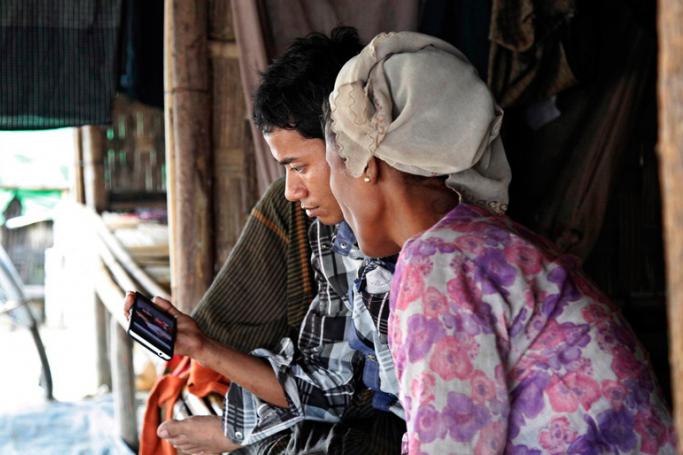 A Rohingya man and his mother watch a movie clip on their mobile phone at the Thet Kel Pyin muslim refugees camp in Sittwe, Rakhine State, western Myanmar. Photo: Nyunt Win/EPA