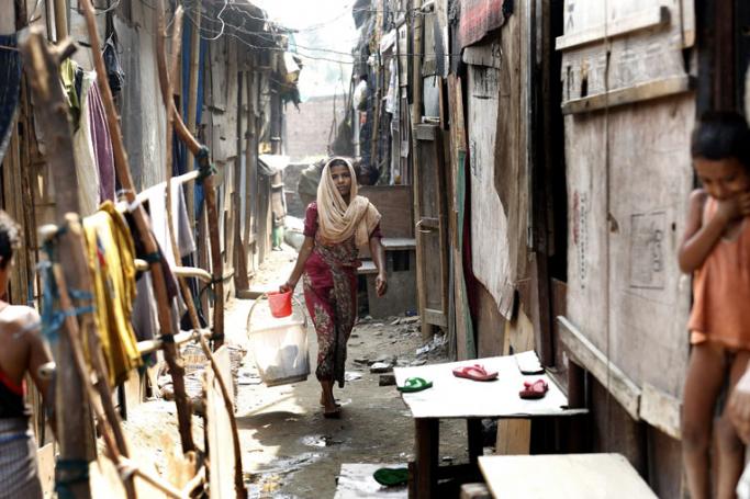Rohingya refugee woman returning home after washing her clothes in a makeshift settlement in Madanpur Khadar in New Delhi, India. Photo: Rajat Gupta/EPA