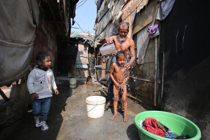A Rohingya Muslim man and a boy take a wash in a makeshift settlement in Madanpur Khadar in New Delhi, India, 10 February 2017. Photo: Rajat Gupta/EPA
