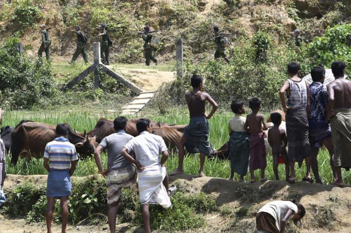 (FILES) In this photograph taken on September 16, 2017, Rohingya Muslim refugees in Jalpatoli refugee camp, in the no-man's land area between Myanmar and Bangladesh, watch as Myanmar soldiers patrol on the other side of the border, near Gumdhum village in Ukhia. Photo: Dominique Faget/AFP
