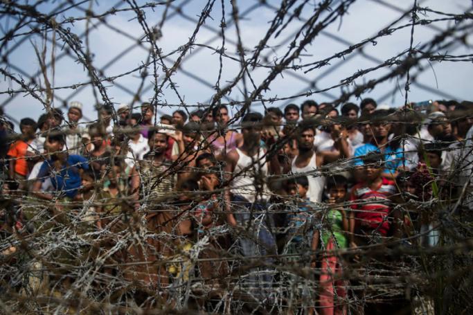 This picture taken from Maungdaw district, Myanmar's Rakhine state on April 25, 2018 shows Rohingya refugees gathering behind a barbed-wire fence in a temporary settlement setup in a "no man's land" border zone between Myanmar and Bangladesh. Photo: Ye Aung Thu/AFP
