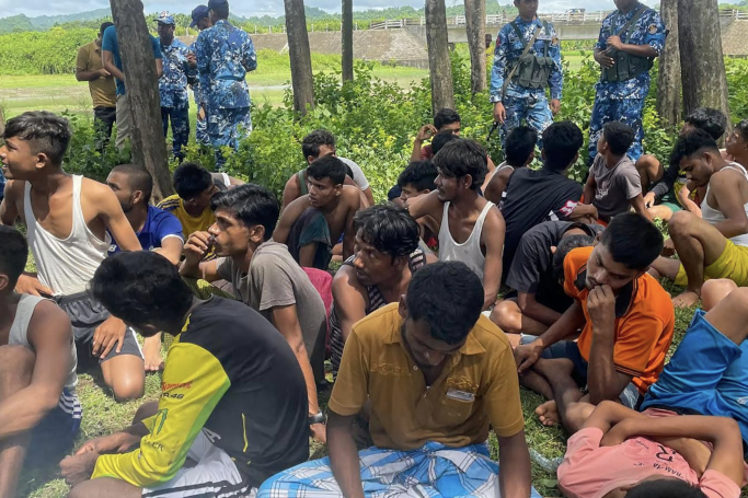 Members of Bangladesh security personnel stand guard beside Rohingya refugees rescued from the sea after a Malaysia bound boat sank off the Bangladesh coast in Teknaf on October 4, 2022. Photo: AFP