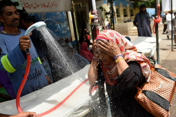 In this file photo, a volunteer showers a woman with water during a heatwave in Karachi. Photo: AFP
