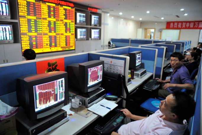 Several investors watch the computer screens showing the stock price information at a securities exchange house in downtown Qingdao city, eastern China's Shandong province. Photo Wu Hong/EPA
