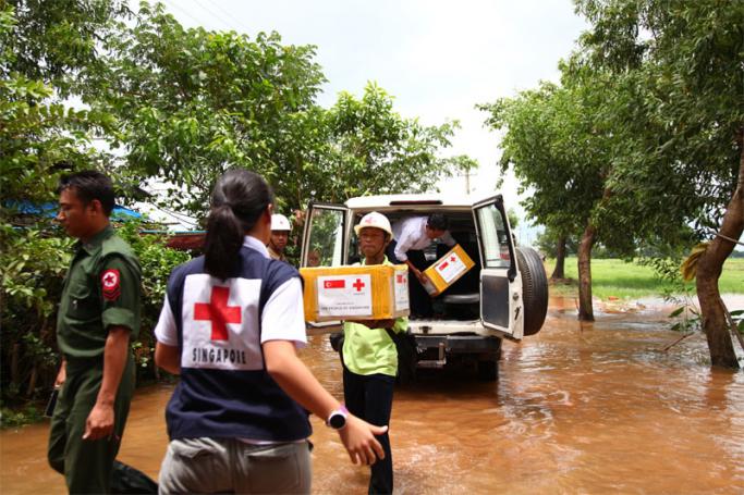 Singapore Red Cross advance team wades through muddy waters to deliver aid to affected communities. Photo: Singapore Red Cross
