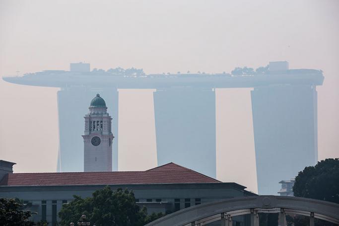 The clocktower of the Victoria Concert Hall (L) stands against the silhouette of the Marina Bay Sands hotel shrouded by haze over Singapore, 26 August 2016. Photo: Wallace Woon/EPA
