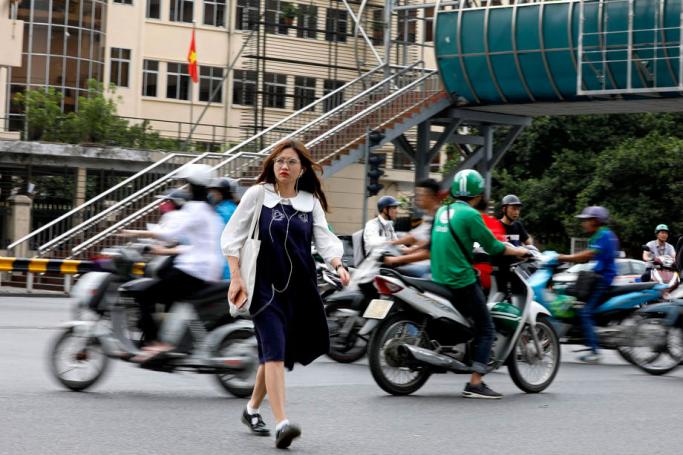 A girl walks across a street near the pedestrian overpass in Hanoi, Vietnam. Photo: EPA