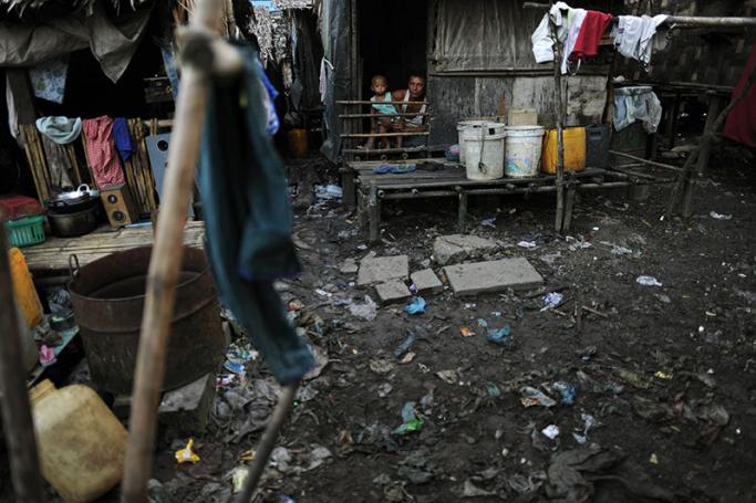 A man and his child peering from their shack in the impoverished slum quarter of Aung Mingalar on the outskirts of Yangon. Photo: AFP
