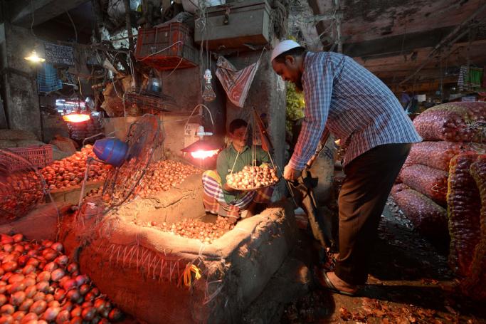A salesman sells onions to a customer at Kawran Bazaar wholesale market in Dhaka on October 2, 2019. Photo: Munir Uz Zaman/AFP