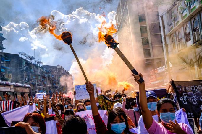 Women carry burning torches as they march during a demonstration against the military coup in Yangon on July 14, 2021. Photo: AFP
