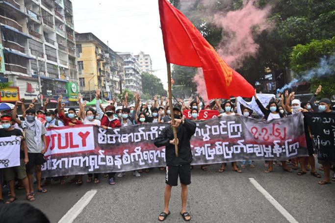 Protesters hold a banner that reads, "Fight by keeping spirits up, destroy the dictatorship from the root by all means" while another holds the Myanmar Student Union flag during a demonstration against the military coup in Yangon on July 7, 2021.  Photo: AFP