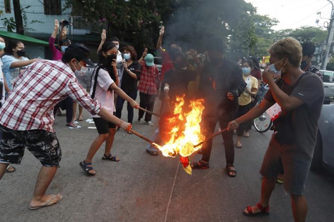(File) Demonstrators flash the three-finger salute and burn the Myanmar National flag during an anti-military coup protest in Yangon, Myanmar, 24 November 2021. Photo: EPA