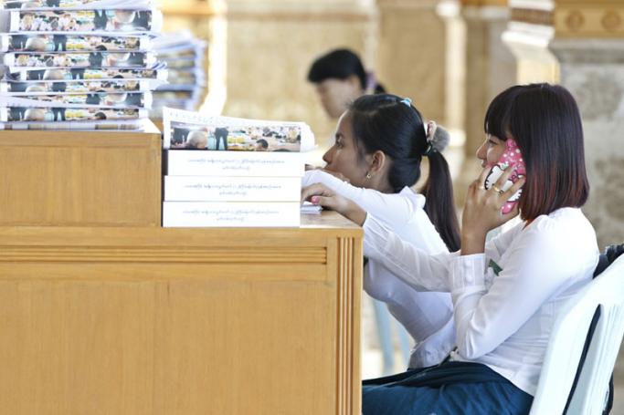 A parliamentry staffer talks on her mobile as she sits at her desk in parliament, Naypyitaw on 17 November 2015. Photo: Nyein Chan Naing/EPA
