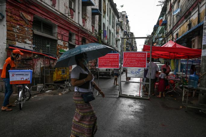 People walk next to a barrier blocking access to minor roads in Yangon on September 11, 2020. Photo: AFP