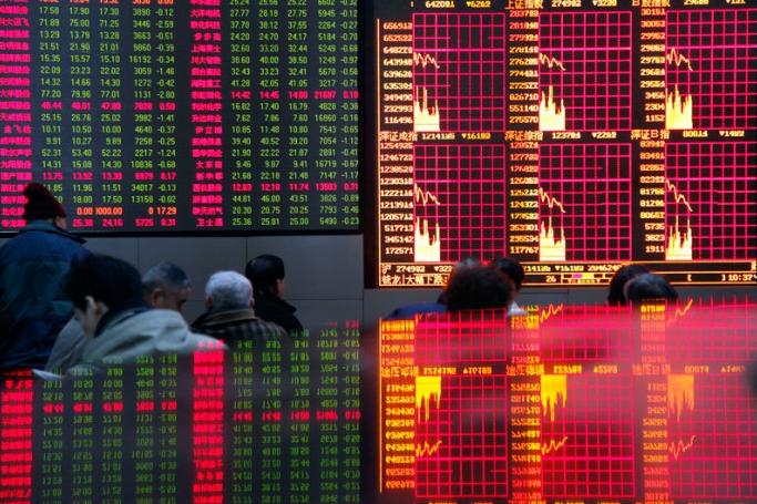 Investors monitor stock prices that are partially reflected on a glass window at a securities exchange house in Shanghai, China. Photo: Qilai Shen/EPA
