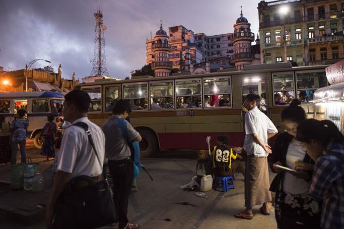 Pedestrians waiting for a bus on a street in Yangon. Photo: Ye Aung Thu/AFP
