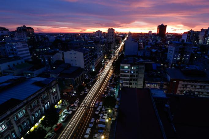 A photo taken with a long exposure shows cars driving along a busy road at sunset in Yangon. Photo: Lynn Bo Bo/EPA