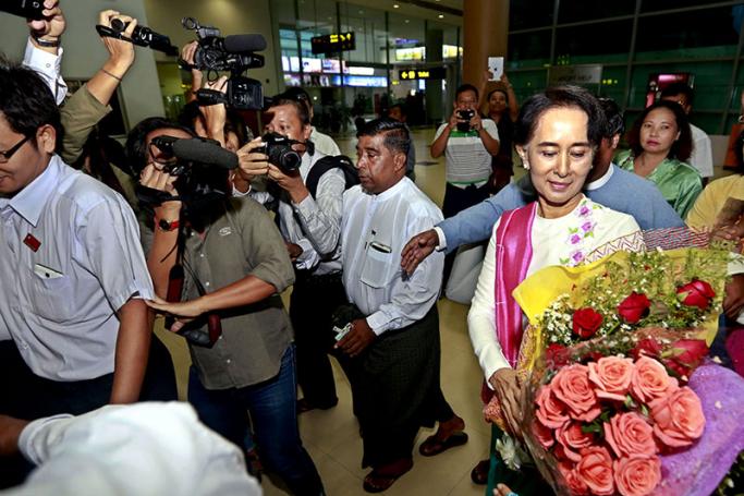 Myanmar opposition leader Aung San Suu Kyi (R) hands over flowers to her assistant as she arrives at Yangon International Airport ahead of her departure for China, in Yangon, Myanmar, 10 June 2015. Photo: Nyein Chan Naing/EPA
