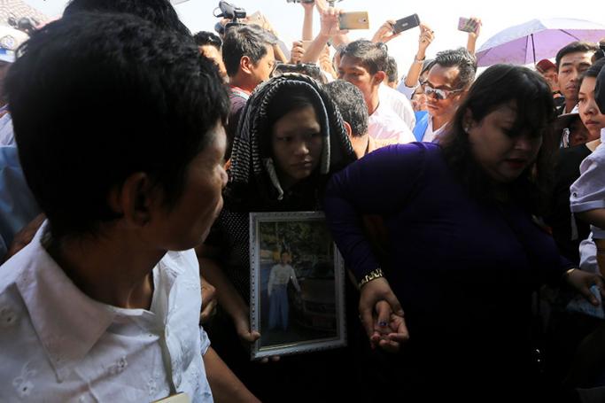Wife of late airport taxi driver Nay Win (C), holds the portrait of her husband during the funeral service at Yay Way cemetery in Yangon on  31 January 2017. Photo: Thet Ko/Mizzima
