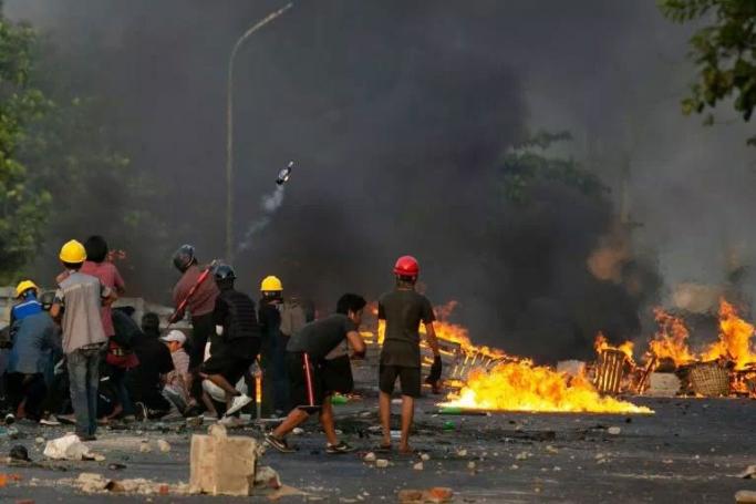 A protester throws a petrol bomb as other take cover behind homemade shields as they confront the police during a crackdown on demonstrations against the military coup in Yangon on March 16, 2021. Photo: AFP