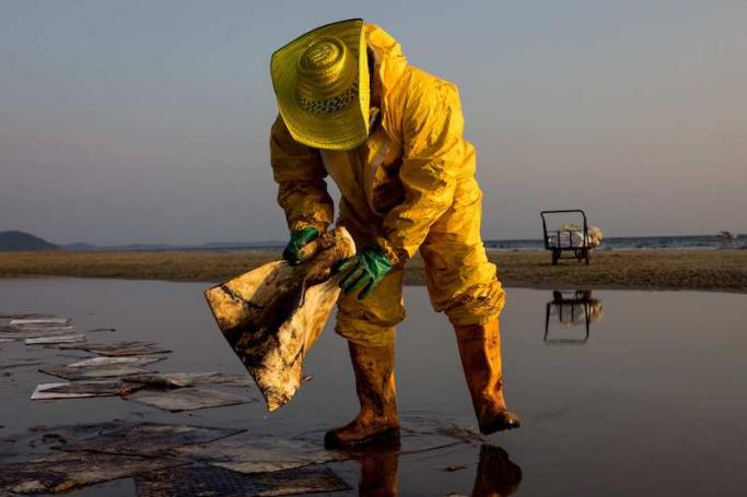 A worker cleans up crude oil on Mae Ram Phueng beach following a spill caused by a leak in an undersea pipeline owned by Star Petroleum Refining Public Company Limited (SPRC) in Rayong on January 29, 2022. (Photo by Jack TAYLOR / AFP)