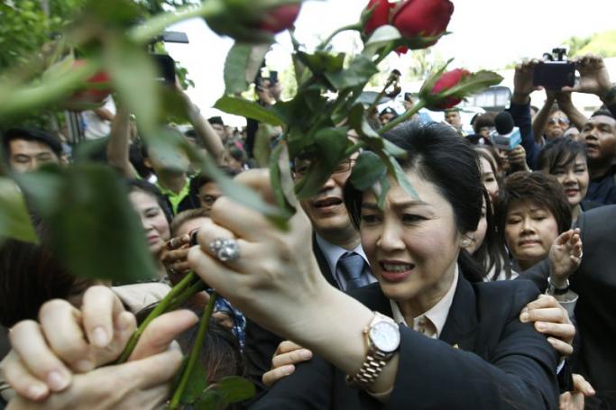 Former Thai prime minister Yingluck Shinawatra (C) receives flowers from supporters as she leaves after a hearing on criminal charges stemming from her government's rice price subsidy, at the Supreme Court's Criminal Division for Holders of Political Positions in Bangkok, Thailand, 19 May 2015. Photo: Narong Sangnak/EPA

