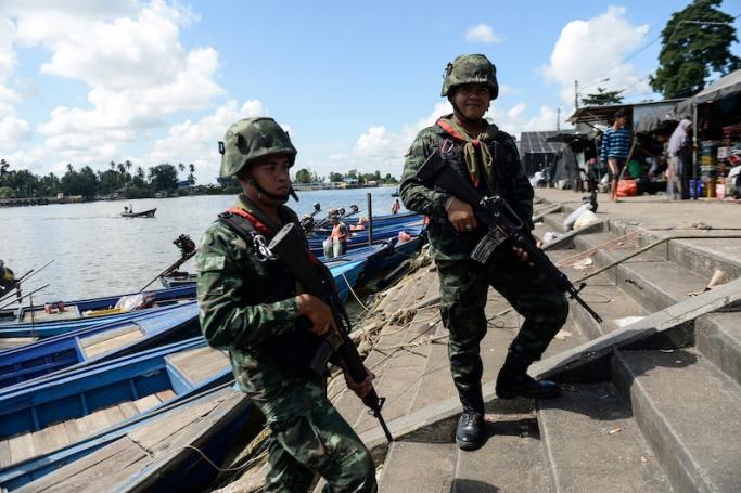 In this photo taken on October 24, 2019, two Royal Thai Army soldiers patrol the Tak Bai riverside market in Thailand's restive southern province of Narathiwat across the Malaysian border, seen in the background. AFP file photo