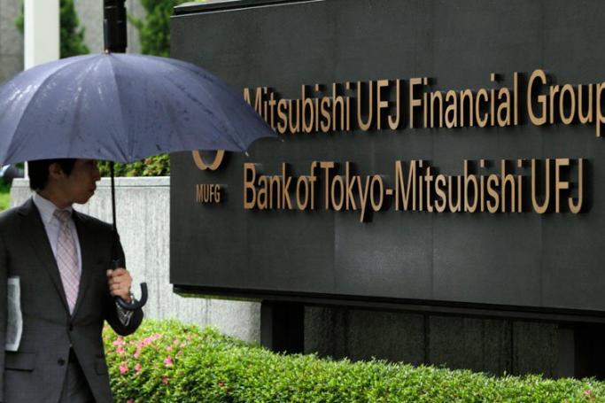 A businessman walking past the headquarters of Japan's largest bank of the Bank of Tokyo-Mitsubishi UFJ, Ltd. and Mitsubishi UFJ Financial Group, Inc. (MUFG) in Tokyo, Japan. Photo: Kimmasa Mayama/EPA
