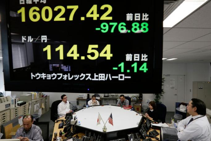 Tokyo money dealers work during an afternoon trade session as a display flashes Tokyo's Nikkei Stock Average in Tokyo, Japan, 9 February 2016. Photo: Kimimasa Mayama/EPA
