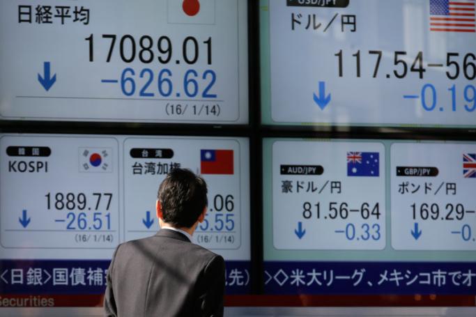 A businessman checks a monitor displaying information onTokyo's Nikkei Stock Average (L) and exchange rate (R) of Japanese yen and US dollars during the afternoon session at a securities branch office in Tokyo, Japan, 14 January 2016. Photo: Kimimasa Mayama/EPA
