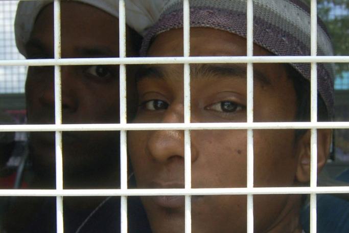Muslim migrants from Bangladesh looks on behind bar on a police truck, days after they were rescued along with ethnic Rohingya refugees following the human trafficking crackdown, at the district hall in Rattaphum district, Songkhla province southern Thailand, 12 May 2015. Photo: Phuchiss Pirunla-Ong/ EPA
