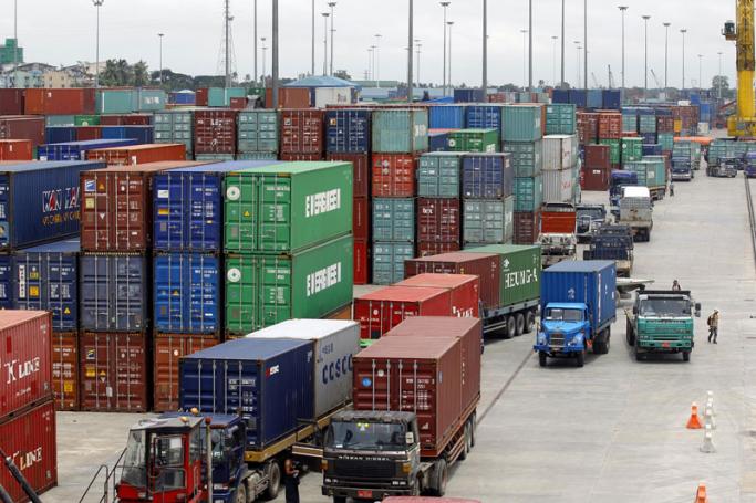 Trucks and forklifts move containers at Aisa World port in Yangon. Photo: Lynn Bo Bo/EPA