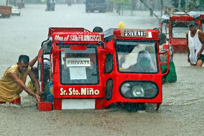 People push a half-submerged tricycle through a flooded street in Agusan del Sur province in Mindanao. (Photo: AFP)