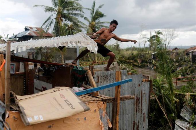 A Filipino villager reinforces a damaged roof in the typhoon-hit town of Pili, Camarines Sur, Philippines, 26 December 2016. Photo: Francis R. Malasig/EPA
