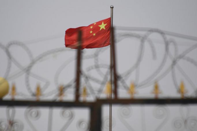 The Chinese flag behind razor wire at one of the many camps in Xinjiang where Muslims are detained on the pretext of preventing terrorism. Photo: AFP