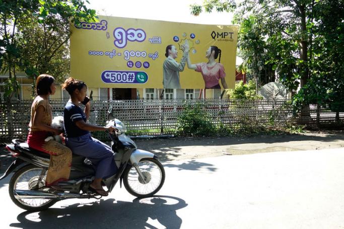 Two Rakhine women ride a motorcycle past a telecommunications advertisement poster in Sittwe, Rakhine state, Myanmar, 22 June 2019. Photo: Nyunt WIn/EPA