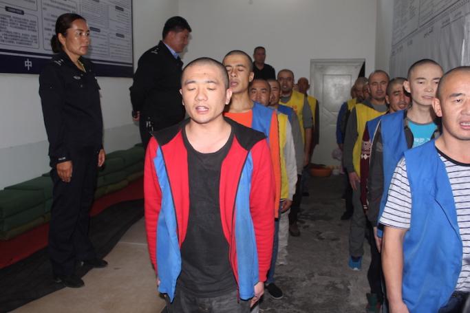 This undated handout image released by The Victims of Communism Memorial Foundation on May 24, 2022, shows detainees guarded by police as they stand in line apparently reciting or singing at the Tekes County Detention Centre in the Xinjiang Region of western China. Photo: AFP