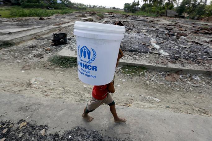 (File) A Muslim boy carries the relief supply from United Nations High Commissioner for Refugees (UNHCR) near the burnt down market in KyetYoePyin village, near Maungdaw town of Bangladesh-Myanmar border, Rakhine State, western Myanmar, 30 March 2017. Photo: EPA