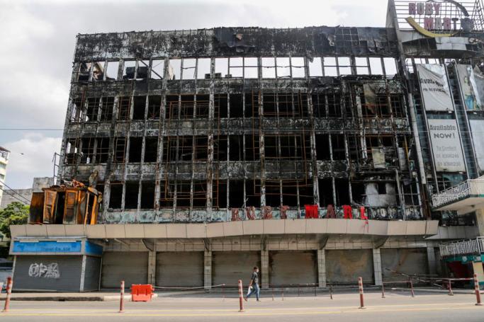 A man walks pass bear a burnt down shopping mall owned by military at downtown area of Yangon, Myanmar, 22 April 2021. Photo: EPA