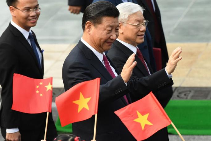 Chinese President Xi Jinping (C) and Vietnam's Communist Party Secretary General Nguyen Phu Trong (R) wave during a welcoming ceremony. Photo: AFP