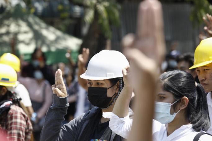 Women hold up the three finger salute during a demonstration against the military coup in Yangon on March 8, 2021. / AFP / STR