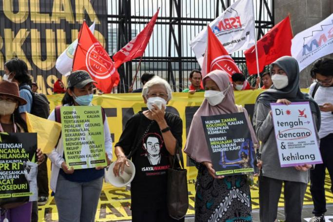 This picture taken on December 5, 2022 shows activists holding a protest against the new criminal code outside the parliament building in Jakarta. Indonesia's parliament approved on December 6 legislation that would outlaw pre-marital sex while making other sweeping changes to the criminal code -- a move critics deemed as a setback to the country's freedoms. (Photo by ADEK BERRY / AFP)