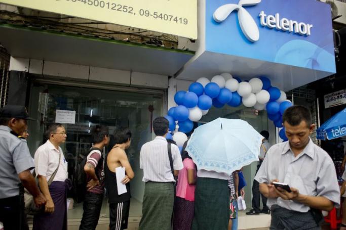 This file photo shows people queuing to buy Telenor's sim card at a local mobile shop in Yangon. The company is selling its business and leaving Myanmar. Photo: AFP