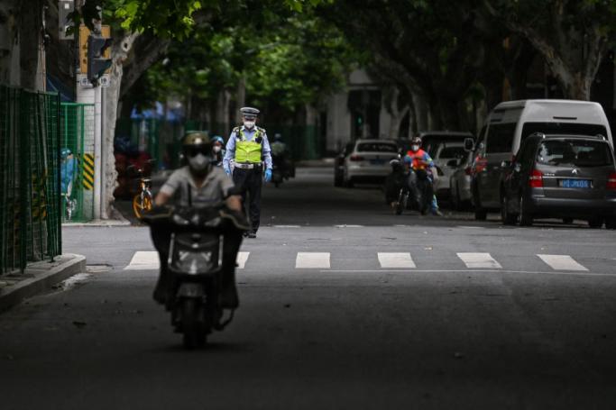 A policeman stands on a street next to a residential area under Covid-19 lockdown in the Xuhui district of Shanghai on June 10, 2022. Photo: Hector RETAMAL / AFP