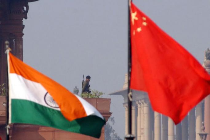 An Indian paramilitary officer is framed by an Indian (L) and Chinese (R) flags as he stands guard near the presidential palace in New Delhi. Photo: AFP