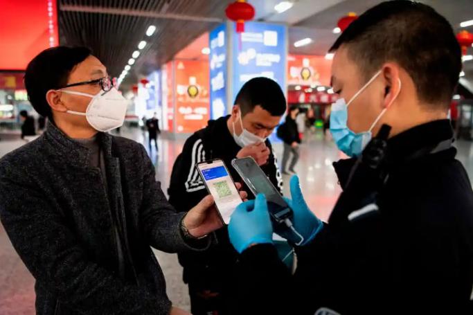 A person wearing a face mask displays a green QR code on his phone to show his health status to security at a train station in Wenzhou, China. Photo: AFP