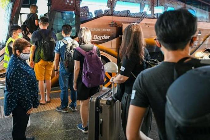 People boarding the bus under the vaccinated travel lane for border crossing passengers to Malaysia’s Southern state of Johor in Singapore on November 29, 2021. Roslan RAHMAN / AFP