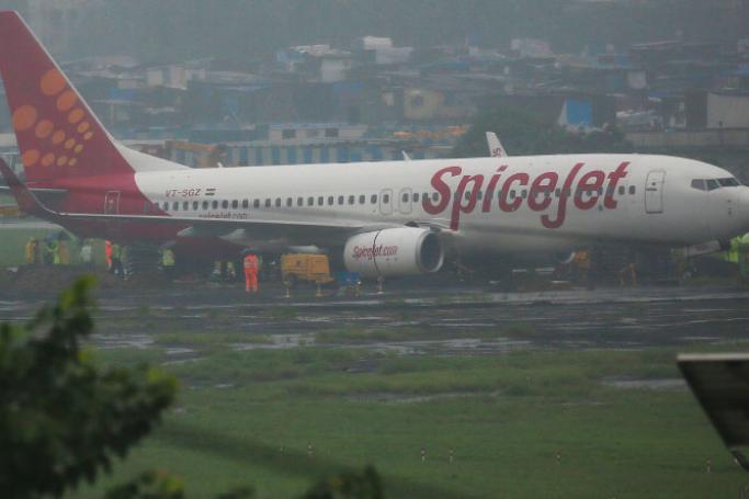 Indian ground and technical staff attempt to remove a SpiceJet plane which became stuck in the mud during overnight rain in Mumba. Photo: AFP